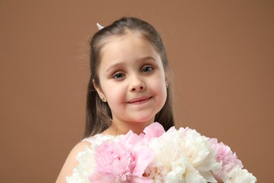 Photo of Cute little girl with bouquet of beautiful peonies on brown background