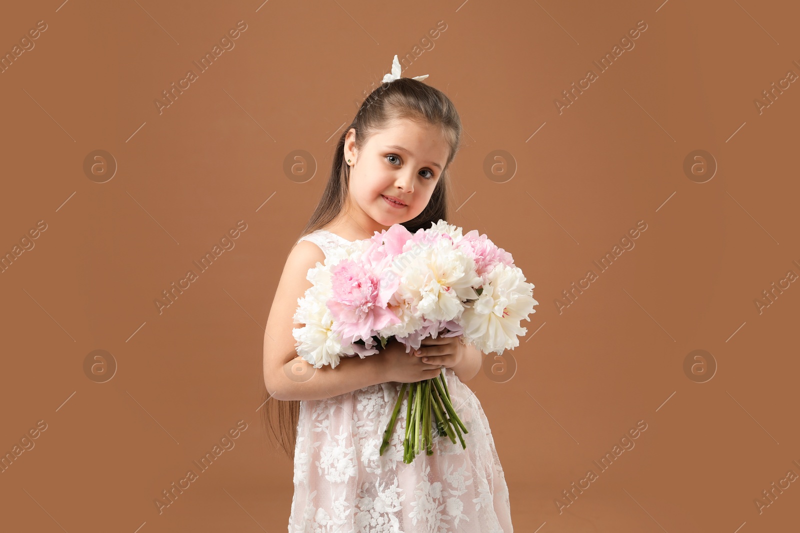Cute little girl with bouquet of beautiful peonies on brown background Photo of Cute little girl with bouquet of beautiful peonies on brown background