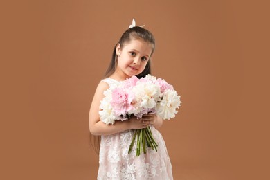 Photo of Cute little girl with bouquet of beautiful peonies on brown background