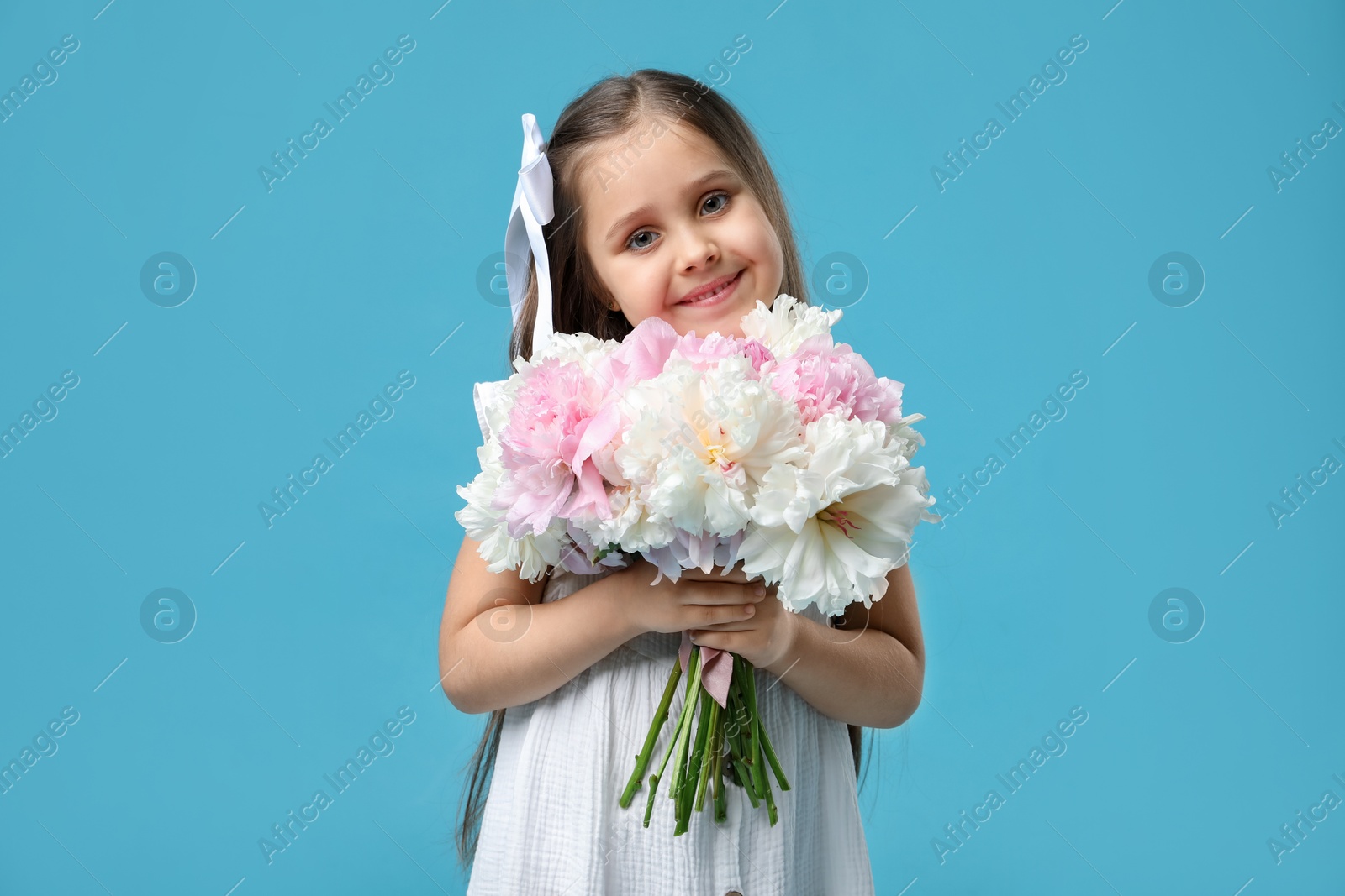 Cute little girl with bouquet of beautiful peonies on light blue background Photo of Cute little girl with bouquet of beautiful peonies on light blue background