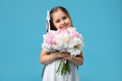 Photo of Cute little girl with bouquet of beautiful peonies on light blue background