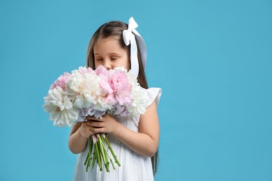 Photo of Cute little girl with bouquet of beautiful peonies on light blue background, space for text