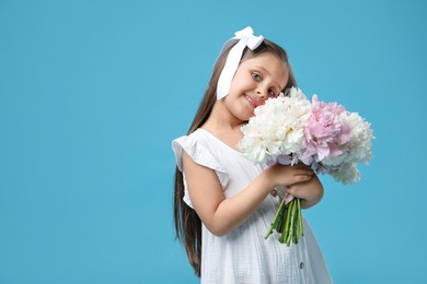 Photo of Cute little girl with bouquet of beautiful peonies on light blue background, space for text