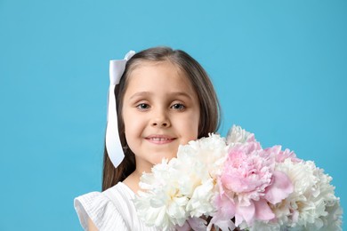 Photo of Cute little girl with bouquet of beautiful peonies on light blue background