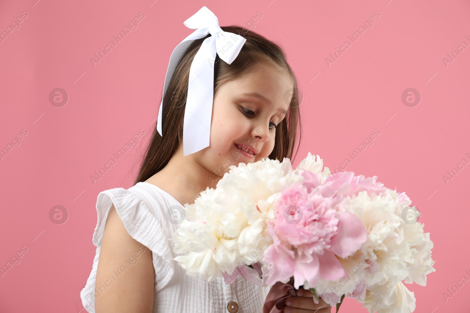 Cute little girl with bouquet of beautiful peonies on pink background Photo of Cute little girl with bouquet of beautiful peonies on pink background