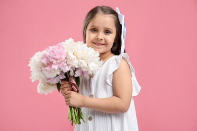 Photo of Cute little girl with bouquet of beautiful peonies on pink background
