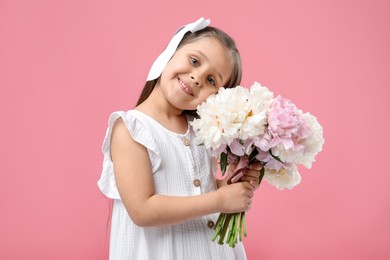 Photo of Cute little girl with bouquet of beautiful peonies on pink background