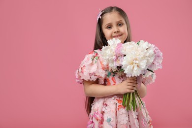 Photo of Cute little girl with bouquet of beautiful peonies on pink background, space for text