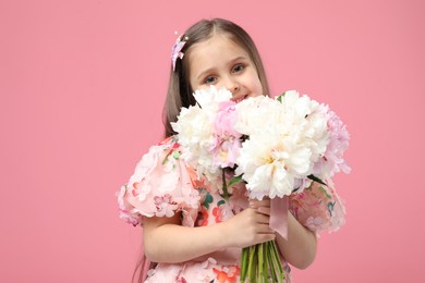 Photo of Cute little girl with bouquet of beautiful peonies on pink background