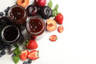 Photo of Different sweet jams in jars and ingredients on white table, flat lay. Space for text