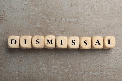 Image of Word Dismissal made of wooden cubes on grey textured background, top view