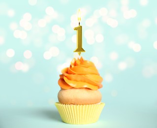 Image of Yummy cupcake with burning golden candle in shape of number 1 on light blue background with blurred lights. Birthday or other special occasion