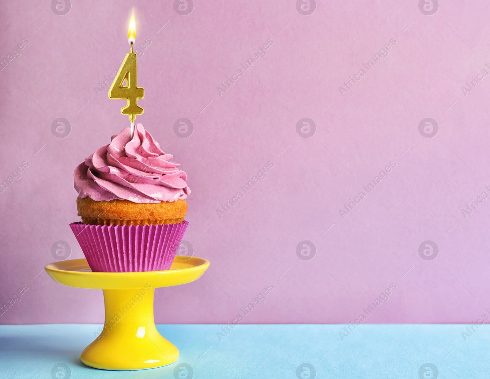 Yummy cupcake with burning golden candle in shape of number 4 on table against violet background, space for text. Birthday or other special occasion Image of Yummy cupcake with burning golden candle in shape of number 4 on table against violet background, space for text. Birthday or other special occasion