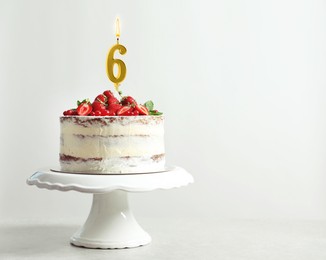 Image of Yummy cupcake with burning golden candle in shape of number 6 on white background, space for text. Birthday or other special occasion