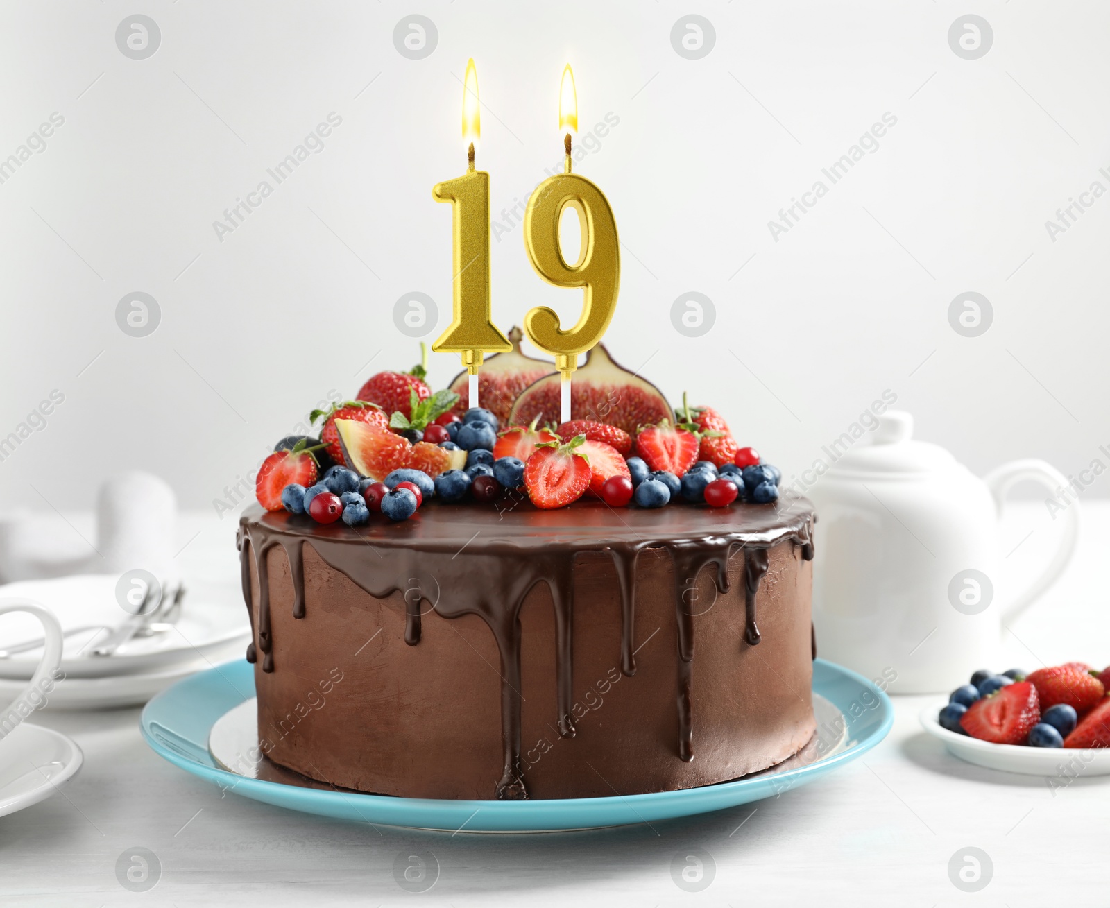 Yummy chocolate cake with fruits and burning number shaped candles on white table. 19th birthday or other special occasion Image of Yummy chocolate cake with fruits and burning number shaped candles on white table. 19th birthday or other special occasion