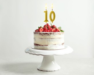 Image of Yummy cake with fruits and burning number shaped candles on white background. 10th birthday or other special occasion
