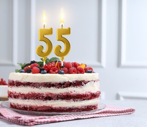 Image of Yummy cake with berries and burning number shaped candles on light table. 55th birthday or other special occasion