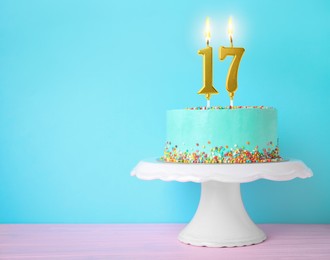 Image of Yummy cake with burning number shaped candles and sprinkles on white table against turquoise background, space for text. 17th birthday or other special occasion