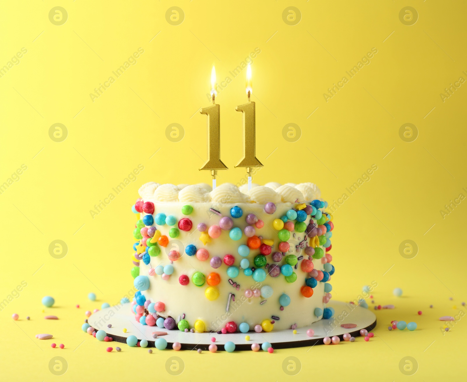 Yummy cake with burning number shaped candles and sprinkles on yellow background. 11th birthday or other special occasion Image of Yummy cake with burning number shaped candles and sprinkles on yellow background. 11th birthday or other special occasion