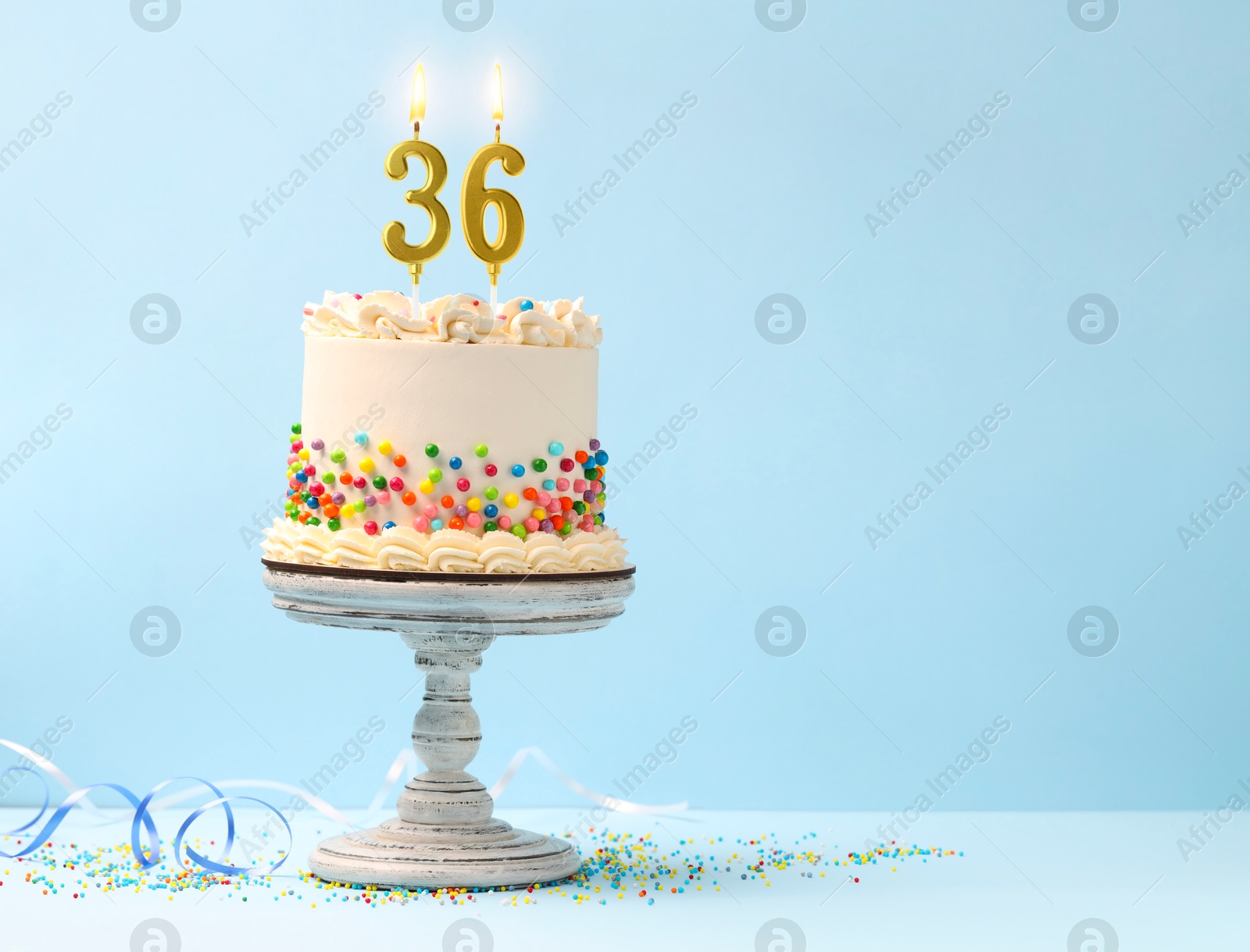 Yummy cake with sprinkles, burning number shaped candles on light blue background, space for text. 36th birthday or other special occasion Image of Yummy cake with sprinkles, burning number shaped candles on light blue background, space for text. 36th birthday or other special occasion