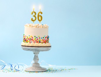 Image of Yummy cake with sprinkles, burning number shaped candles on light blue background, space for text. 36th birthday or other special occasion