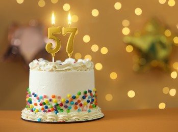 Image of Yummy cake with burning number shaped candles against blurred lights, space for text. 57th birthday or other special occasion