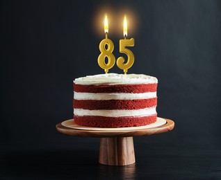Image of Yummy cake with burning number shaped candles on black background. 85th birthday or other special occasion