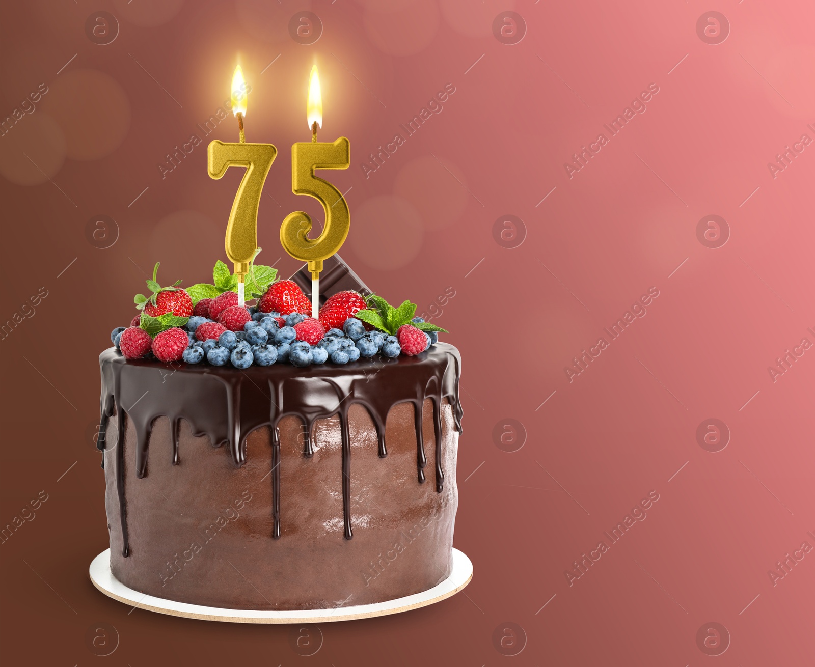 Image of Yummy chocolate cake with berries and burning number shaped candles on color gradient background, space for text. 75th birthday or other special occasion