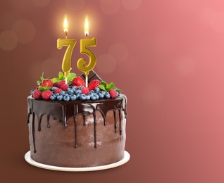 Image of Yummy chocolate cake with berries and burning number shaped candles on color gradient background, space for text. 75th birthday or other special occasion