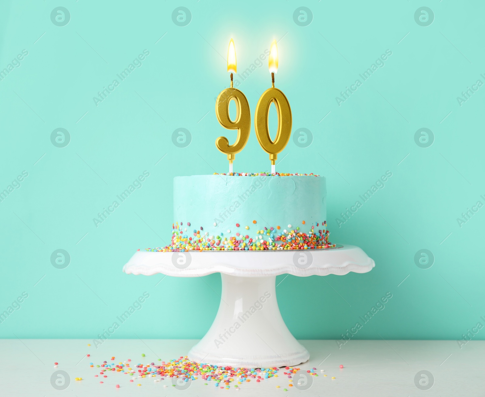 Yummy cake with burning number shaped candles and sprinkles on white table against turquoise background. 90th birthday or other special occasion Image of Yummy cake with burning number shaped candles and sprinkles on white table against turquoise background. 90th birthday or other special occasion