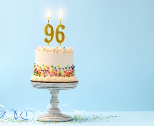 Image of Yummy cake with sprinkles, burning number shaped candles and serpentine streamer on light blue background, space for text. 96th birthday or other special occasion