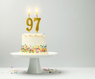 Image of Yummy cake with burning number shaped candles and sprinkles on light background, space for text. 97th birthday or other special occasion