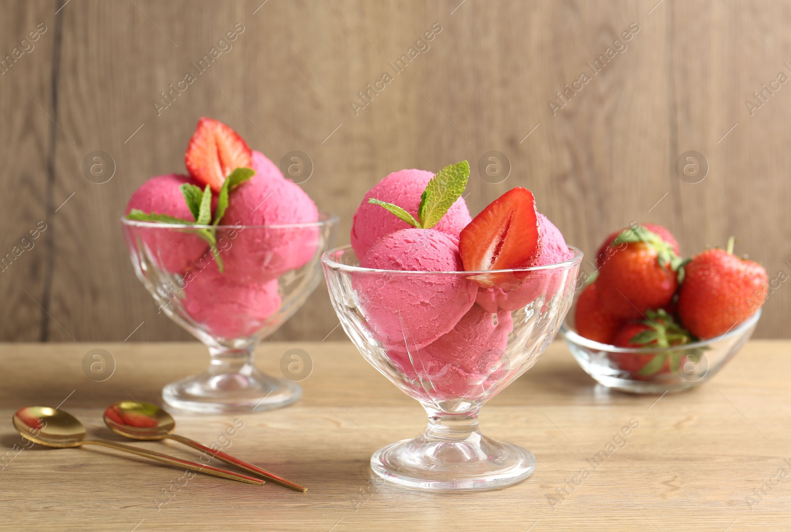 Refreshing sorbet, strawberries, mint and spoons on wooden table, closeup Photo of Refreshing sorbet, strawberries, mint and spoons on wooden table, closeup