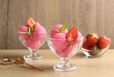 Photo of Refreshing sorbet, strawberries, mint and spoons on wooden table, closeup