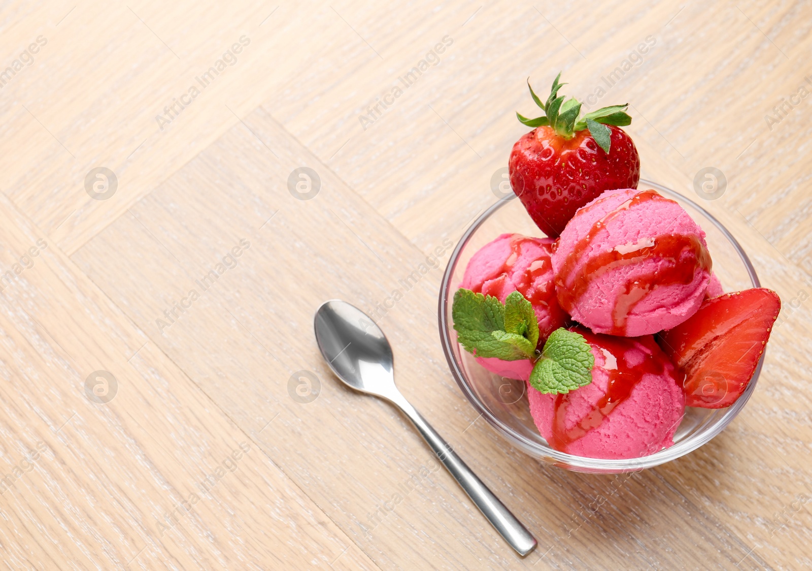 Photo of Refreshing sorbet with syrup, strawberries and mint in bowl on wooden table, above view. Space for text