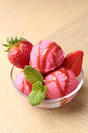 Photo of Refreshing sorbet with syrup, strawberries and mint in bowl on wooden table