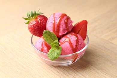 Photo of Refreshing sorbet with syrup, strawberries and mint in bowl on wooden table, closeup