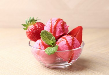 Photo of Refreshing sorbet with syrup, strawberries and mint in bowl on wooden table, closeup