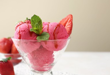 Photo of Refreshing sorbet with syrup, strawberries and mint in dessert bowl on white table against beige background, closeup. Space for text