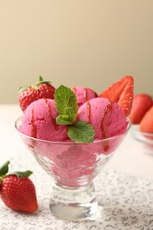 Photo of Refreshing sorbet with syrup, strawberries and mint in dessert bowl on white table against beige background, closeup