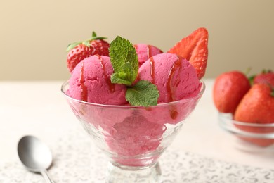 Photo of Refreshing sorbet with syrup, strawberries and mint in dessert bowl on white table against beige background, closeup