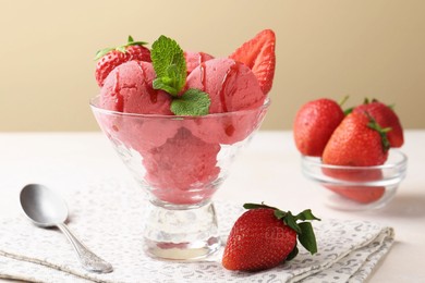 Photo of Refreshing sorbet with syrup, strawberries and mint in dessert bowl on white table against beige background, closeup