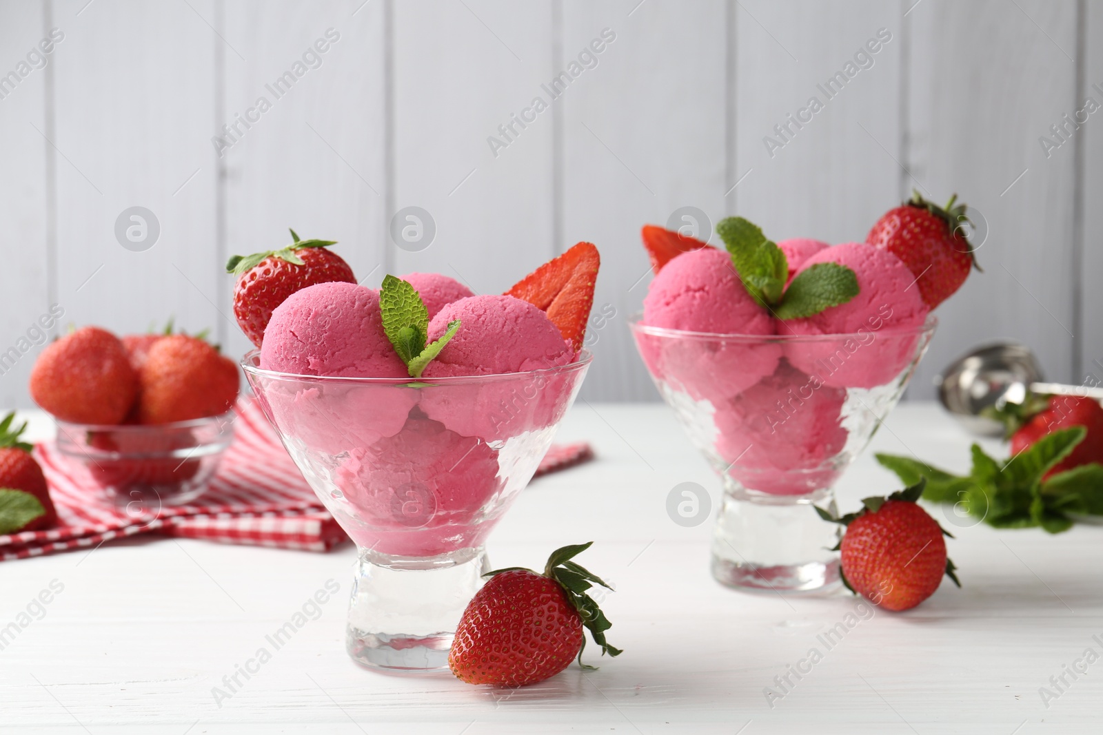 Photo of Refreshing sorbet, strawberries and mint in dessert bowls on white wooden table against grey background, closeup
