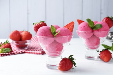 Photo of Refreshing sorbet, strawberries and mint in dessert bowls on white wooden table against grey background, closeup