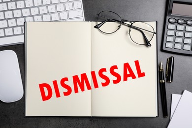 Image of Word Dismissal in notebook on grey table. Office workplace, top view