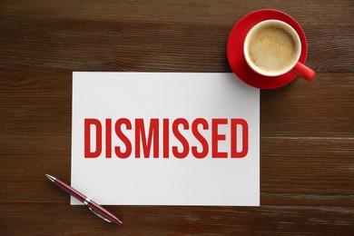 Image of Paper with word Dismissed, pen and coffee on wooden table, top view