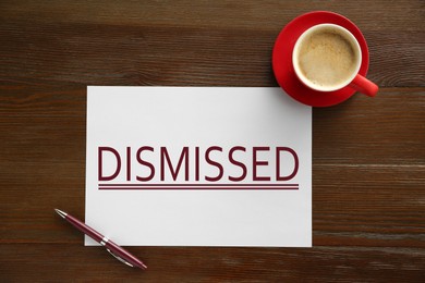 Image of Paper with word Dismissed, pen and coffee on wooden table, top view