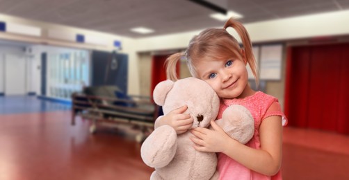 Image of Cute little girl with toy bear in hallway of children's hospital. Banner design