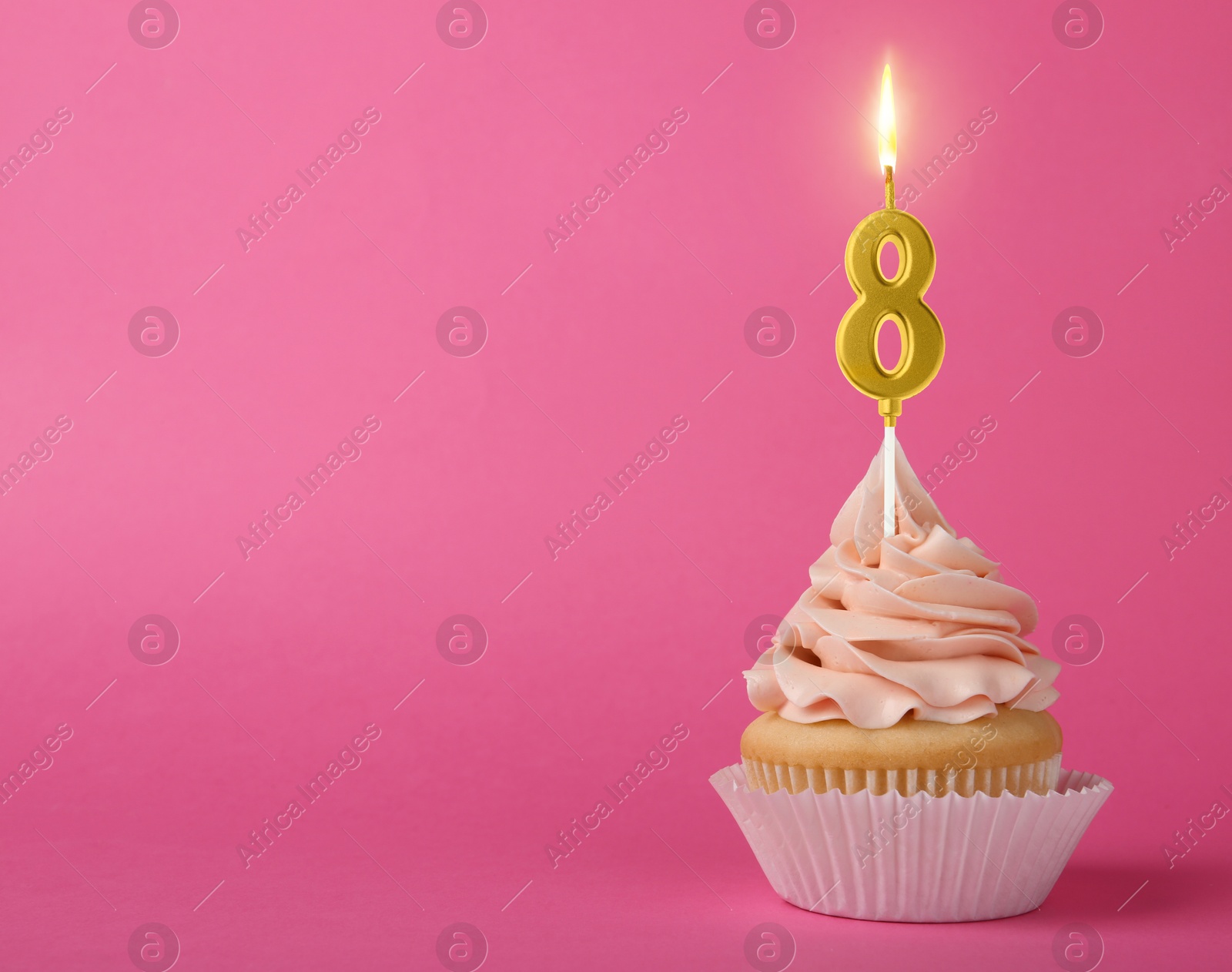 Image of Yummy cupcake with burning golden candle in shape of number 8 on pink background, space for text. Birthday or other special occasion