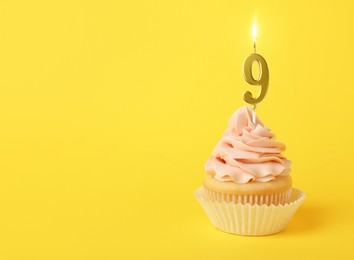 Image of Yummy cupcake with burning golden candle in shape of number 9 on yellow background, space for text. Birthday or other special occasion